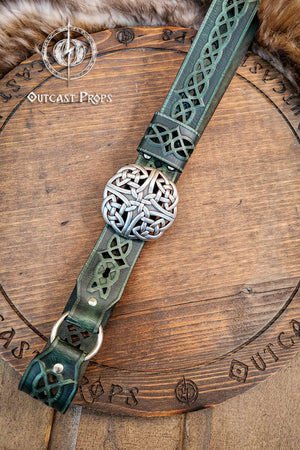 Decorative leather belt with intricate designs on a wooden surface, featuring the brand 'Outcast Props'. Celtic knot leather belt silver buckle larp belt for ren fair fantasy costume celtic belt unisex leather belt for renaissance outfit