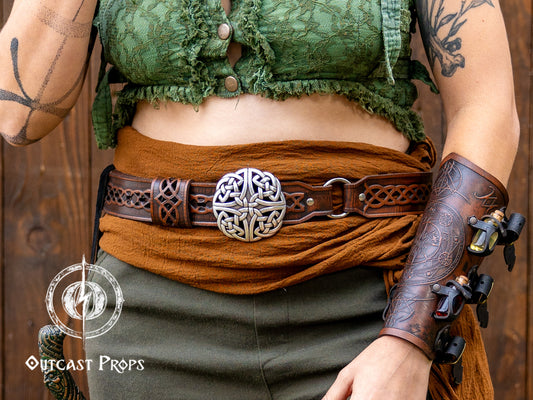 Person wearing a green top, brown belt with a decorative buckle, and green pants against a wooden background. Celtic knot leather belt silver buckle larp belt for ren fair fantasy costume celtic belt unisex leather belt for renaissance outfit