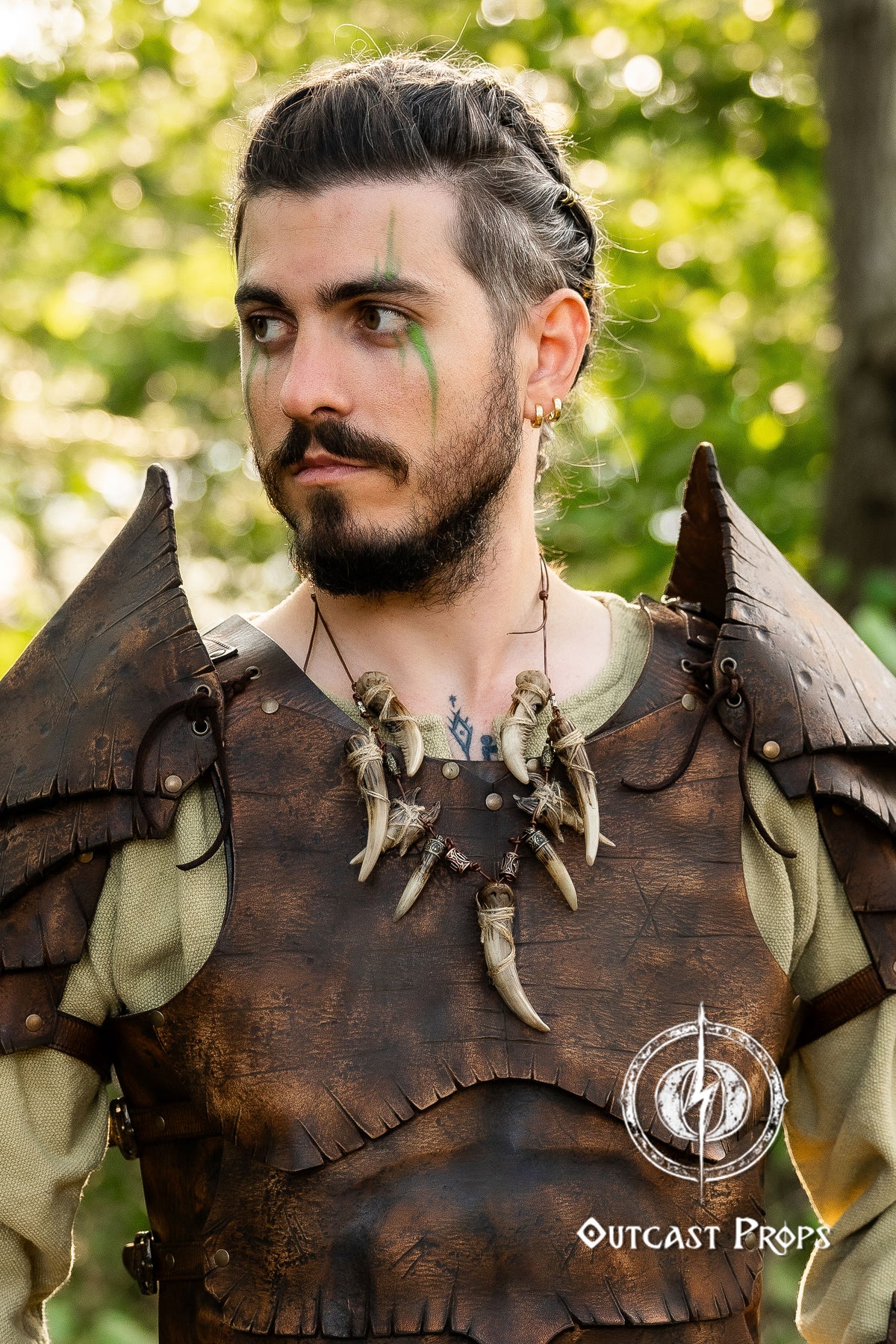 Man in a detailed costume with armor and feathers, standing outdoors. Celtic Tusk Necklace Viking ornament Tribal Shaman Druid with realistic resin fangs Orc LARP cosplay and post-apocalypse marauder