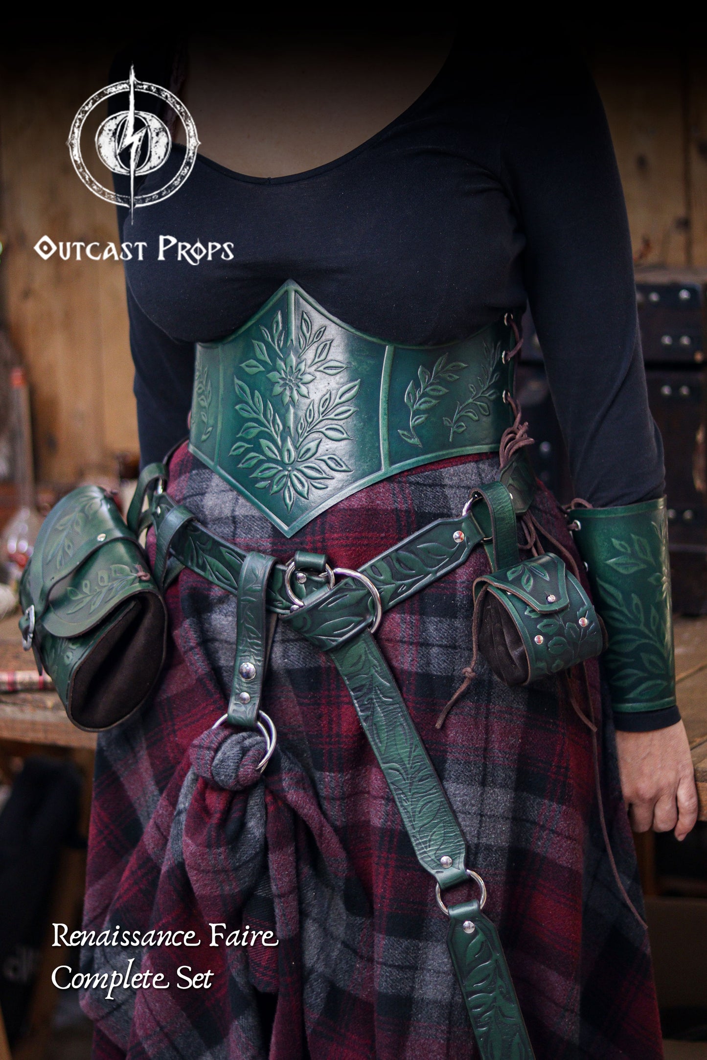 Full view of the complete green floral leather set, featuring the underbust corset belt, bracers and matching embossed pouches worn with a plaid fantasy skirt. The outfit reflects an elegant renaissance faire and elven aesthetic, mixing botanical embossing with handcrafted aged leather. Ideal for herbalist cosplay, witchcore characters, druidic costumes and LARP events. The coordinated pieces create a polished cinematic look.