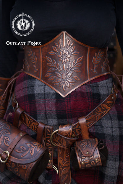 Floral leather coin pouch attached to a wide belt in a full Renaissance Faire outfit, handcrafted in premium vegetable tanned leather with elegant embossed leaves. The set is worn by an elf, herbalist or witch character for LARP, renfaire or medieval events, showing how the pouch hangs securely from the belt loop. Perfect for carrying coins or small items while keeping the aesthetic of elven accessories and renaissance noble costumes.