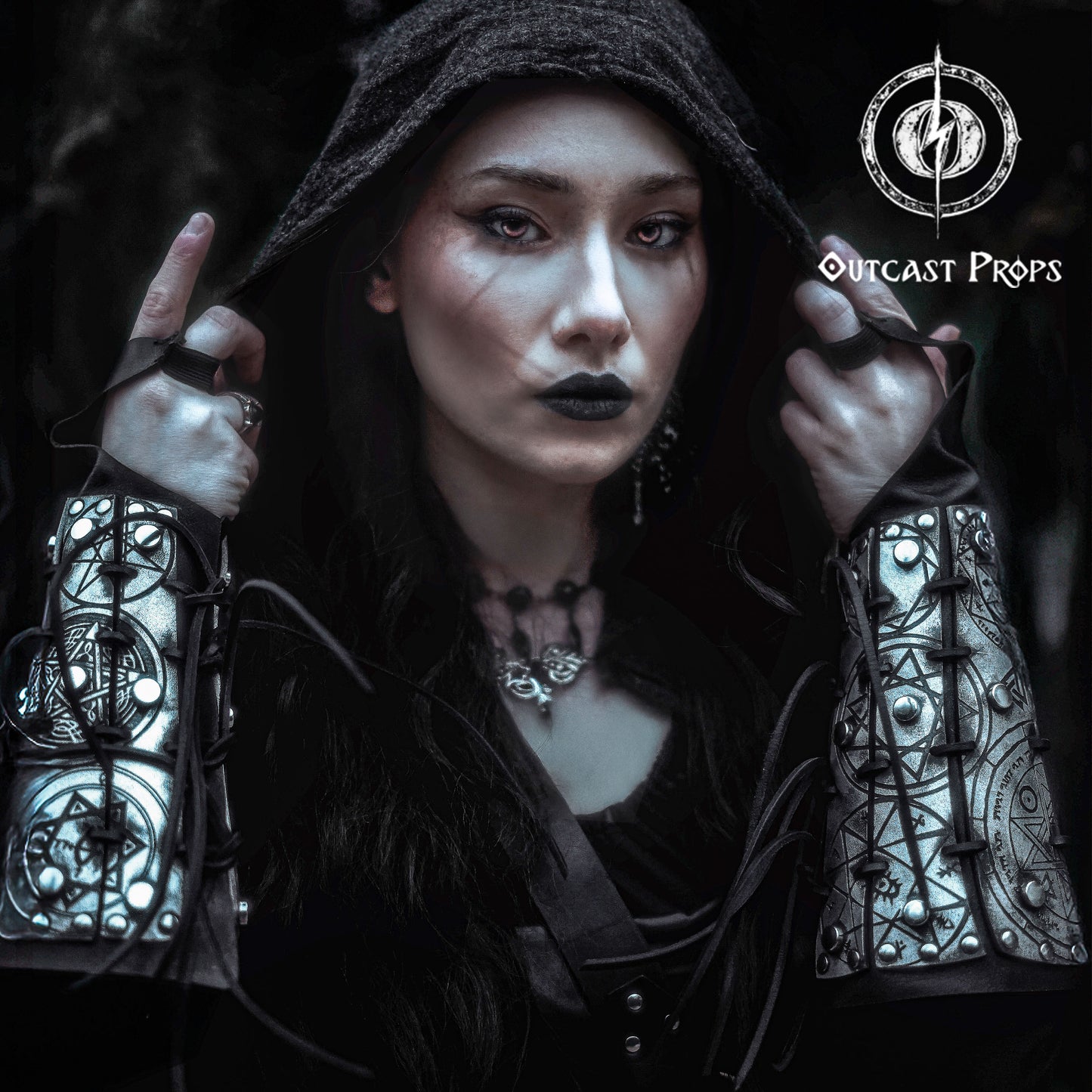 Portrait of a dark sorceress wearing silver engraved bracers covered in arcane sigils and protective symbols. The bracers are laced with black cord and have a bold metallic finish. Perfect for LARP, gothic fashion, or witch cosplay. These leather bracers evoke the power of magic and the occult, designed to channel energy and dominate ritual scenes. A striking fantasy accessory for spellcasters, necromancers, or shadow mages.