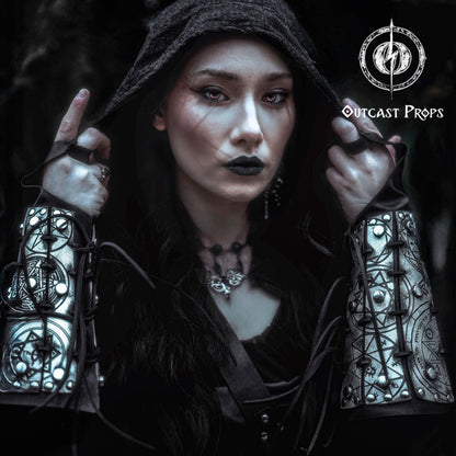 Portrait of a dark sorceress wearing silver engraved bracers covered in arcane sigils and protective symbols. The bracers are laced with black cord and have a bold metallic finish. Perfect for LARP, gothic fashion, or witch cosplay. These leather bracers evoke the power of magic and the occult, designed to channel energy and dominate ritual scenes. A striking fantasy accessory for spellcasters, necromancers, or shadow mages.