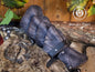 Black dragon scale leather bracer displayed on a fur and wooden background with medieval props. This handcrafted piece is ideal for LARP warriors, Viking cosplay, and medieval reenactment. Made from vegetable-tanned leather and detailed with Outcast Props’ unique weathering and aging finish, the scales evoke power and mystery—perfect for orc armor, dark ranger costumes, or monster hunter kits.