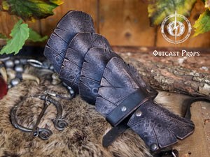 Black dragon scale leather bracer displayed on a fur and wooden background with medieval props. This handcrafted piece is ideal for LARP warriors, Viking cosplay, and medieval reenactment. Made from vegetable-tanned leather and detailed with Outcast Props’ unique weathering and aging finish, the scales evoke power and mystery—perfect for orc armor, dark ranger costumes, or monster hunter kits.