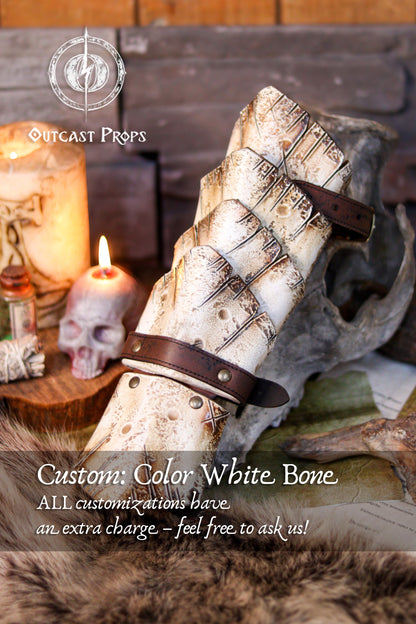 Bone-white custom version of the Dragon Scale Bracer presented on a medieval-style altar with candles and skulls. A unique accessory for necromancer LARP characters, undead warriors, or pale elven cosplays. Crafted in vegetable-tanned leather and detailed with a bone-effect finish. Fully handmade and customizable, this vambrace brings eerie presence to your fantasy gear.