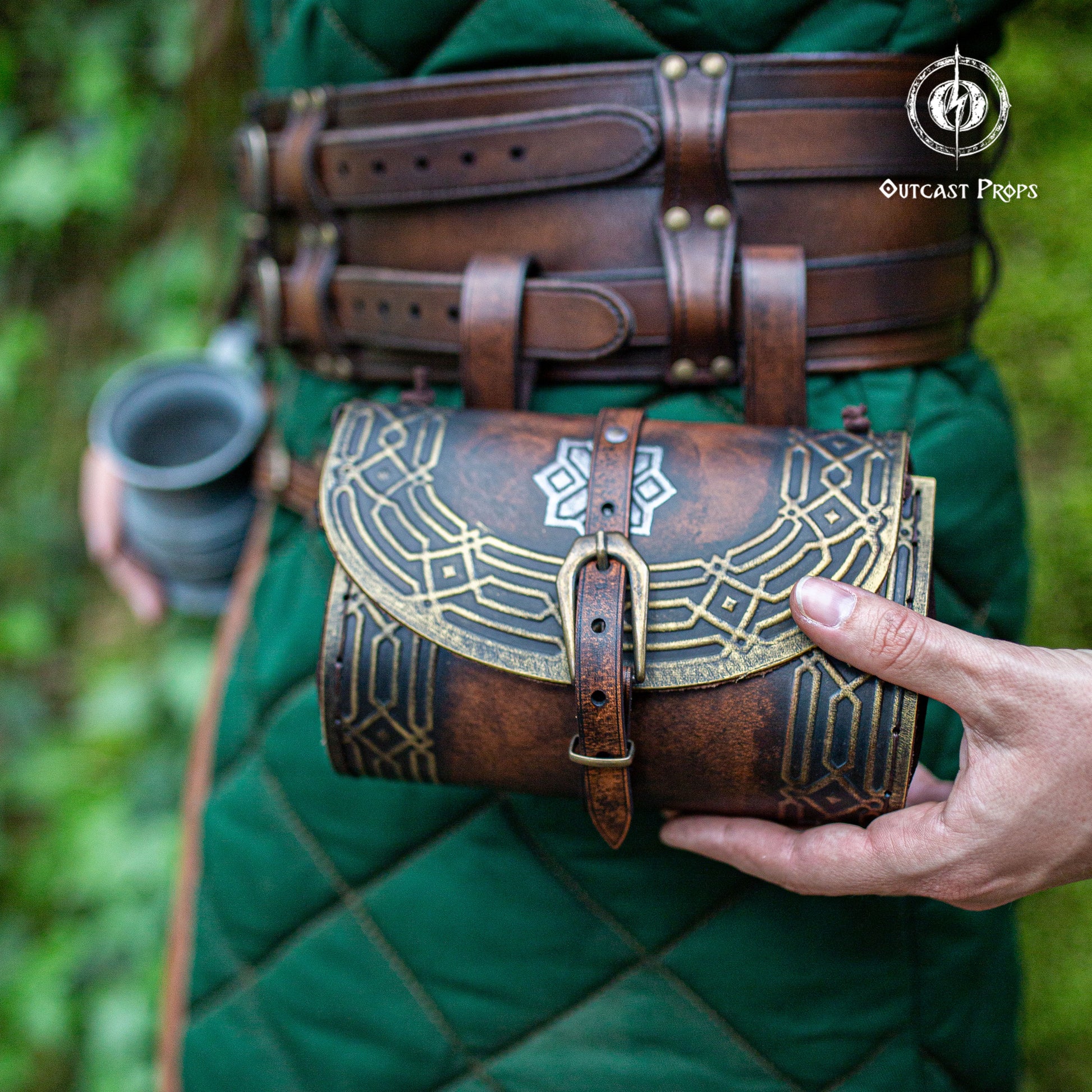 Darwf Bag for LARP. Person wearing a green outfit with a brown leather pouch featuring intricate designs, held in front of a blurred natural background.