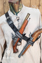 Edward Kenway pirate cosplay. A woman poses outdoors wearing a brown leather pirate baldric loaded with two ornThree-quarter frontal view of a mannequin wearing the Edward Kenway pirate baldric in black leather, with two pistols secured in the holsters. The floral embossed strap crosses the chest diagonally, combining rugged function and stylish design. Inspired by legendary pirate captains from Assassin’s Creed and Black Sails, this accessory is made for LARP, historical reenactments and immersive cosplay.