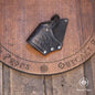 Handcrafted black leather flintlock holster with embossed decorative tooling and nickel hardware displayed on a wooden surface. This cross draw holster is designed for pirate costumes, LARP, cosplay and renaissance fair outfits. Leather gun holster suitable for medium sized flintlock pistol props, featuring a secure retention strap, durable vegetable tanned leather construction and authentic historical styling for pirate, privateer and naval officer characters.