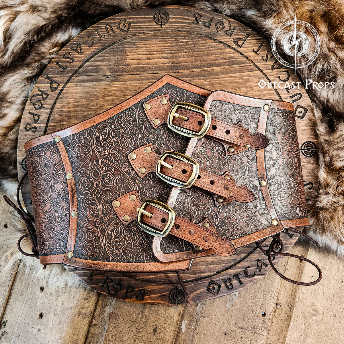Leather underbust with embossed design and gold buckles on a wooden background. Leather Corset. Elegant underbust por cosplay and larp. 