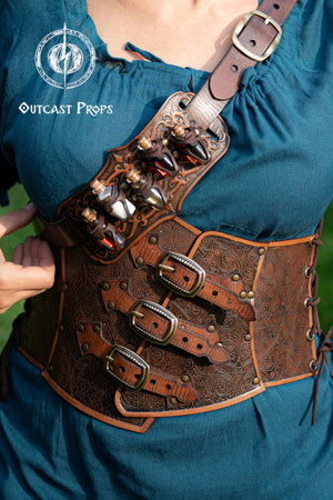 Person wearing a detailed leather harness with decorative elements, branded 'Outcast Props'. Embroidered Leather Underbust Corset – Elegant Brown Waist Cincher for Noble LARP Outfits, Steampunk and Fantasy Glamour