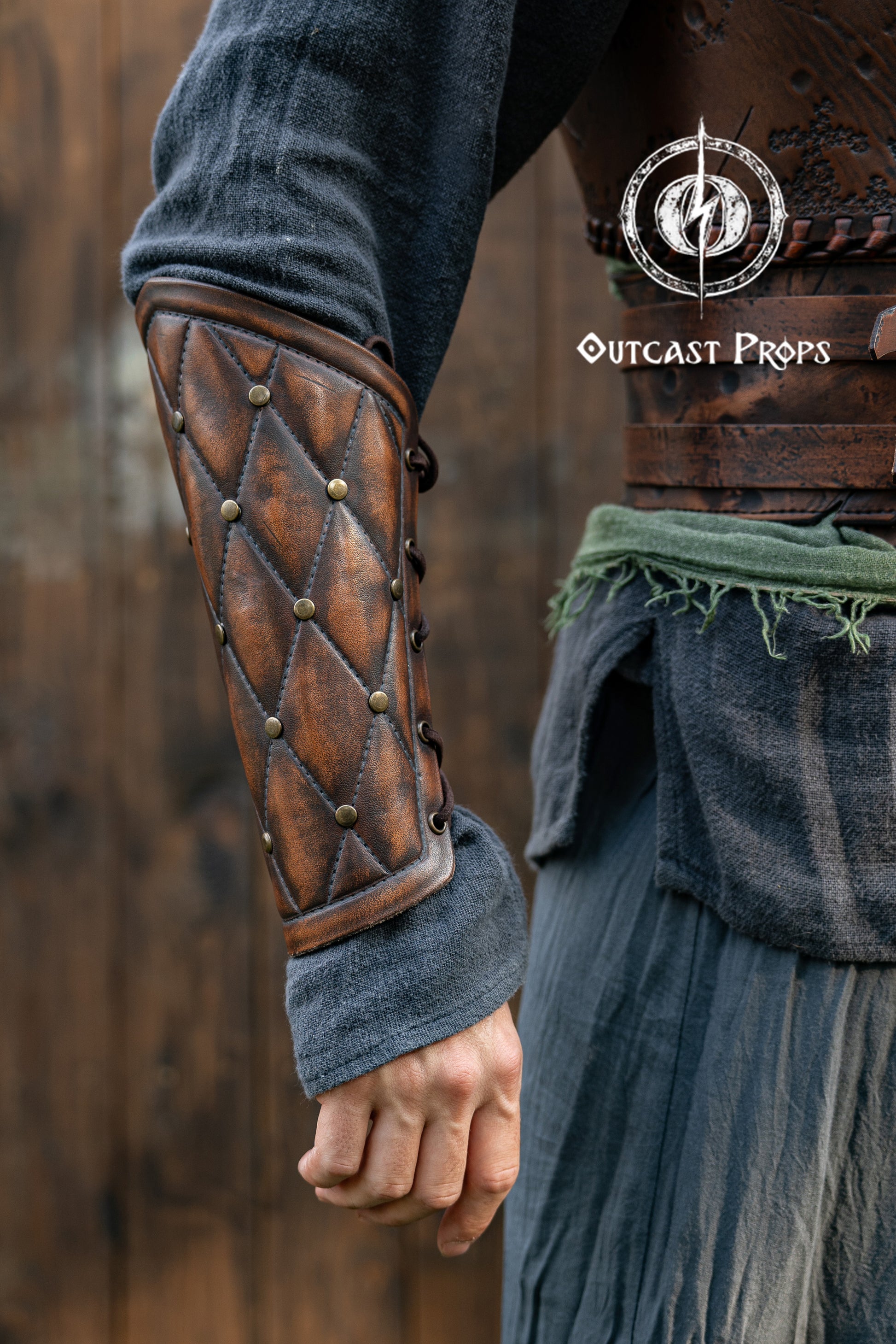 Close-up of a person wearing a detailed leather arm guard with 'Outcast Props' branding. Falken leather bracers for noble costume LARP outfit medieval fantasy accessories for Ren Faire cosplay arm guards for knight character gear