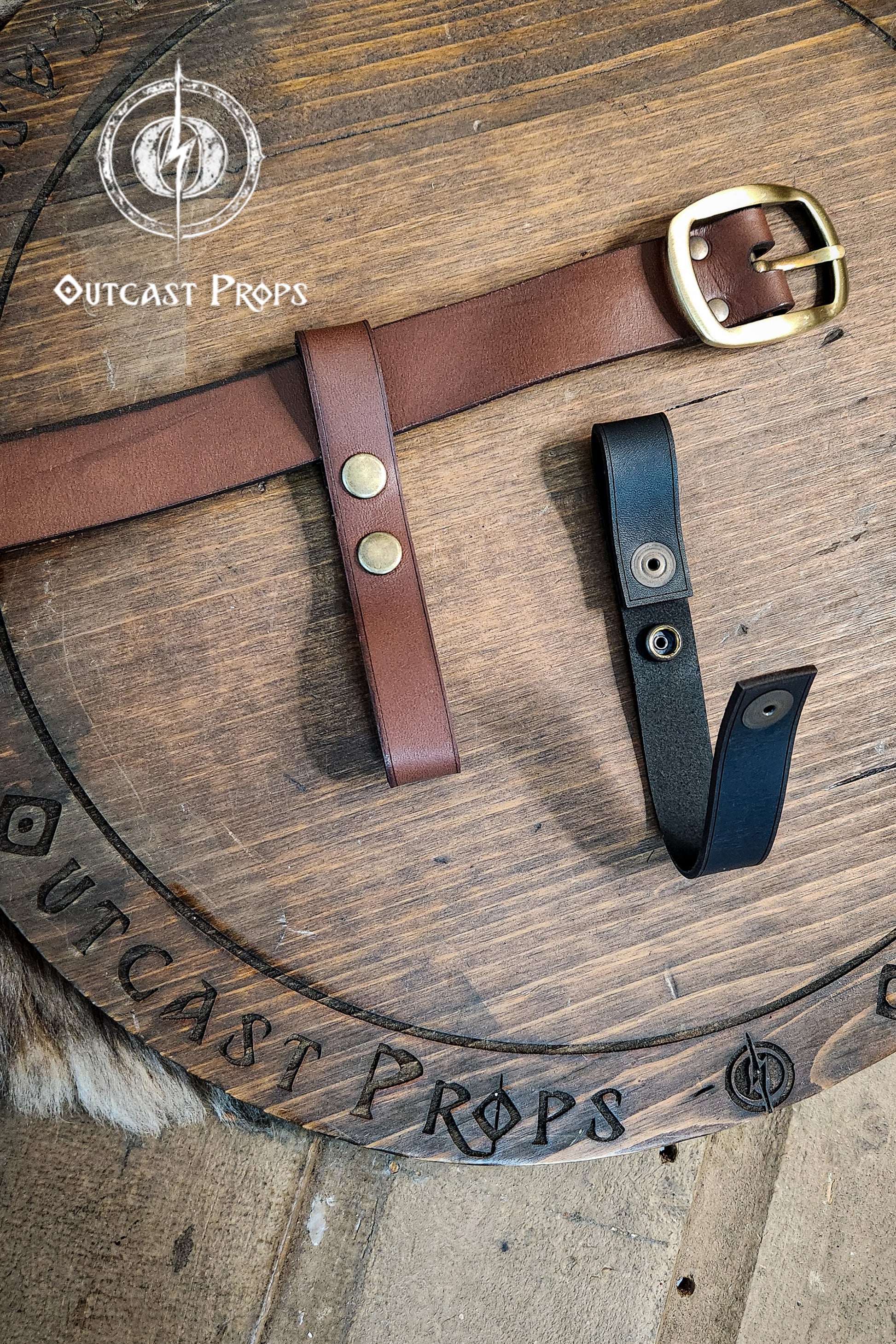 Brown leather belt with gold buckle on a wooden surface with 'Outcast Props' branding. Versatile Leather Belt Clasp for LARP, Cosplay & Medieval Accessories - Handcrafted Vegetal Tanned Attachment