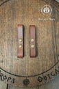 Leather belt pair of clasp mug holder belt strap medieval accessory set of two for LARP cosplay renaissance fair Handcrafted Vegetal Tanned. Two brown leather straps with brass rivets on a wooden surface with 'Outcast Props' branding.