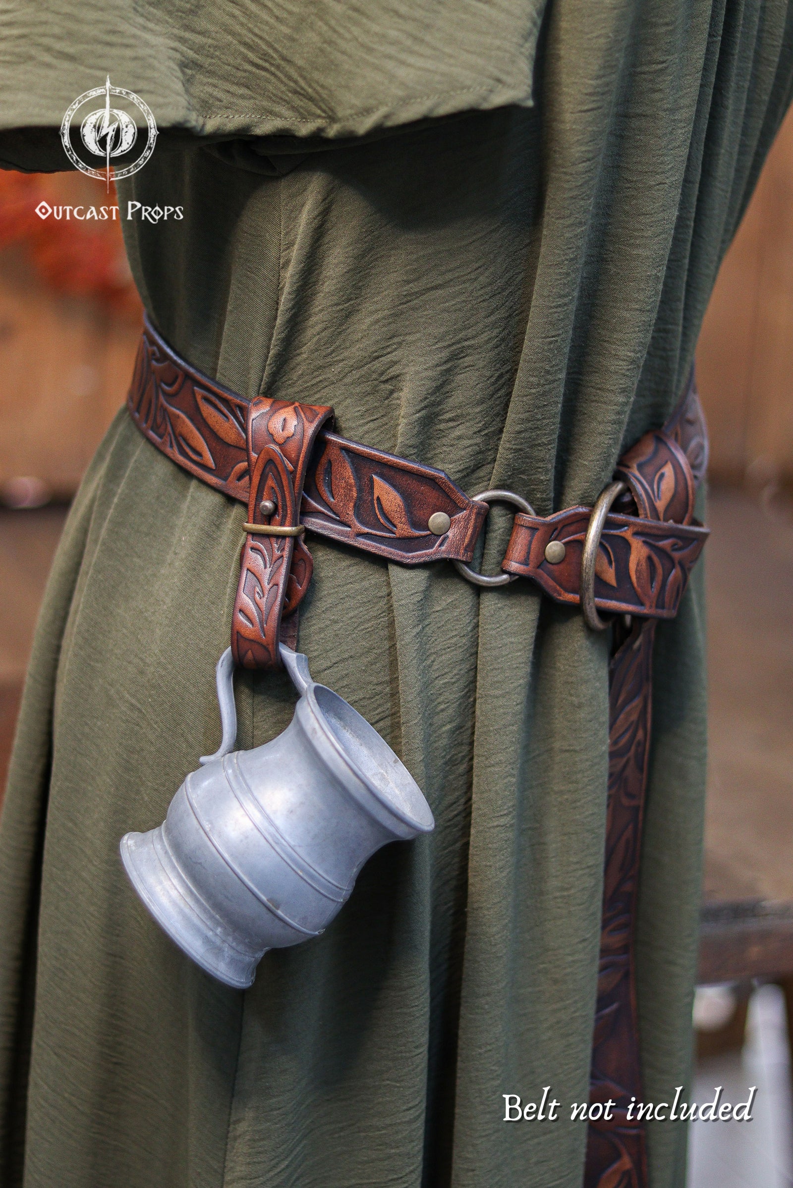 Brown leather belt with a silver cup holder worn by a person in green fabric, Outcast Props logo visible.