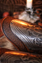 Macro close-up of the engraved floral metalwork on a fantasy bracer, showing the detailed etching and high-quality leather trim. This image emphasizes craftsmanship and is perfect for showcasing handmade LARP armor or cosplay accessories with a noble or elven aesthetic.