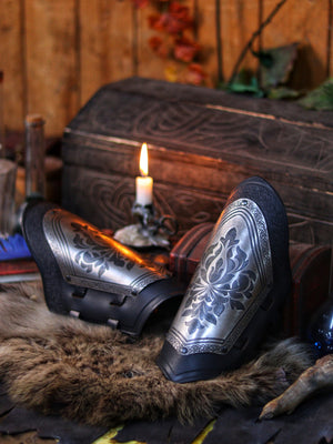 Bracers with engraved steel plates and black leather resting on fur beside a carved chest and candle. The perfect mix of noble elegance and fantasy gear, ideal for medieval roleplay, knight costumes, or detailed cosplay props. Rich warm tones enhance the immersive, handcrafted feel.