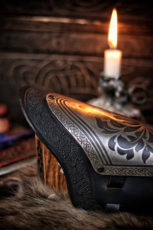Macro close-up of the engraved floral metalwork on a fantasy black leather bracer, showing the detailed etching and high-quality leather trim. This image emphasizes craftsmanship and is perfect for showcasing handmade LARP armor or cosplay accessories with a noble or elven aesthetic.