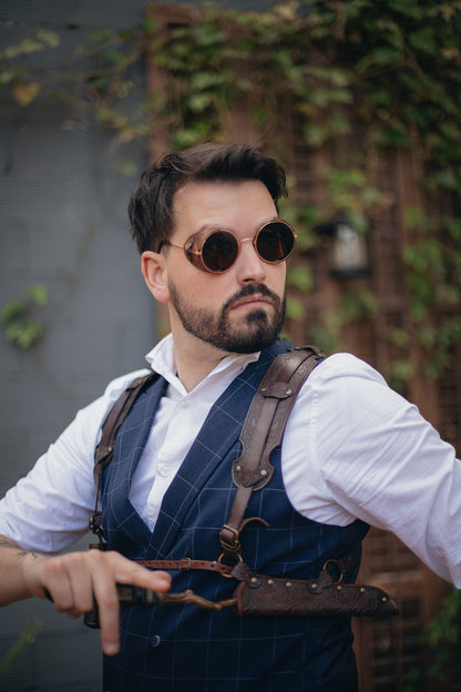 Ornated Magic Wand shoulder Holster full-grain leather with potions for wizards and witches. Dark Academy style. MACUSA Cosplay and LARP. A person wearing a white shirt and a shoulder holster in a patterned fabric. The holster is brown, made of leather, and designed to hold a wand.