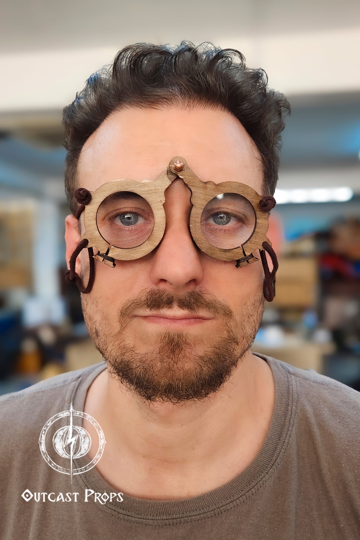 Man wearing a wooden medieval glasses with Outcast Props logo in the corner. Medieval eyeglasses steampunk glasses larp alchemist glasses renaissance fair eyewear medieval spectacles fantasy glasses cosplay accessory. Vintage-Inspired Alchemist Spectacles: Medieval LARP Steampunk Eyewear for Renaissance Fairs & Cosplay
