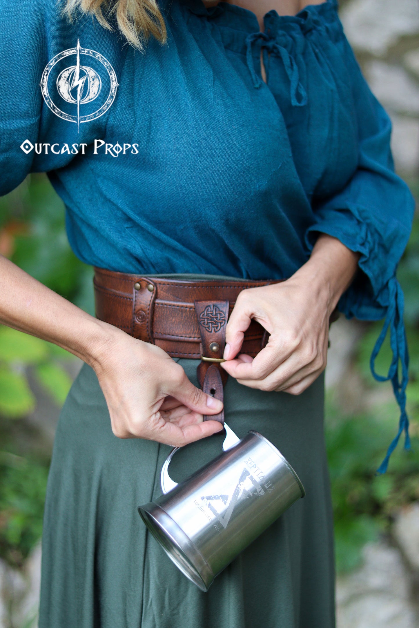 Person holding a metal mug with a leather belt and Outcast Props logo in the corner. Medieval Leather Tankard Strap: Renaissance Faire Belt up to 6 cm or 2,4 inches. Accessory for key, rope, mug. Celtic or viking costume