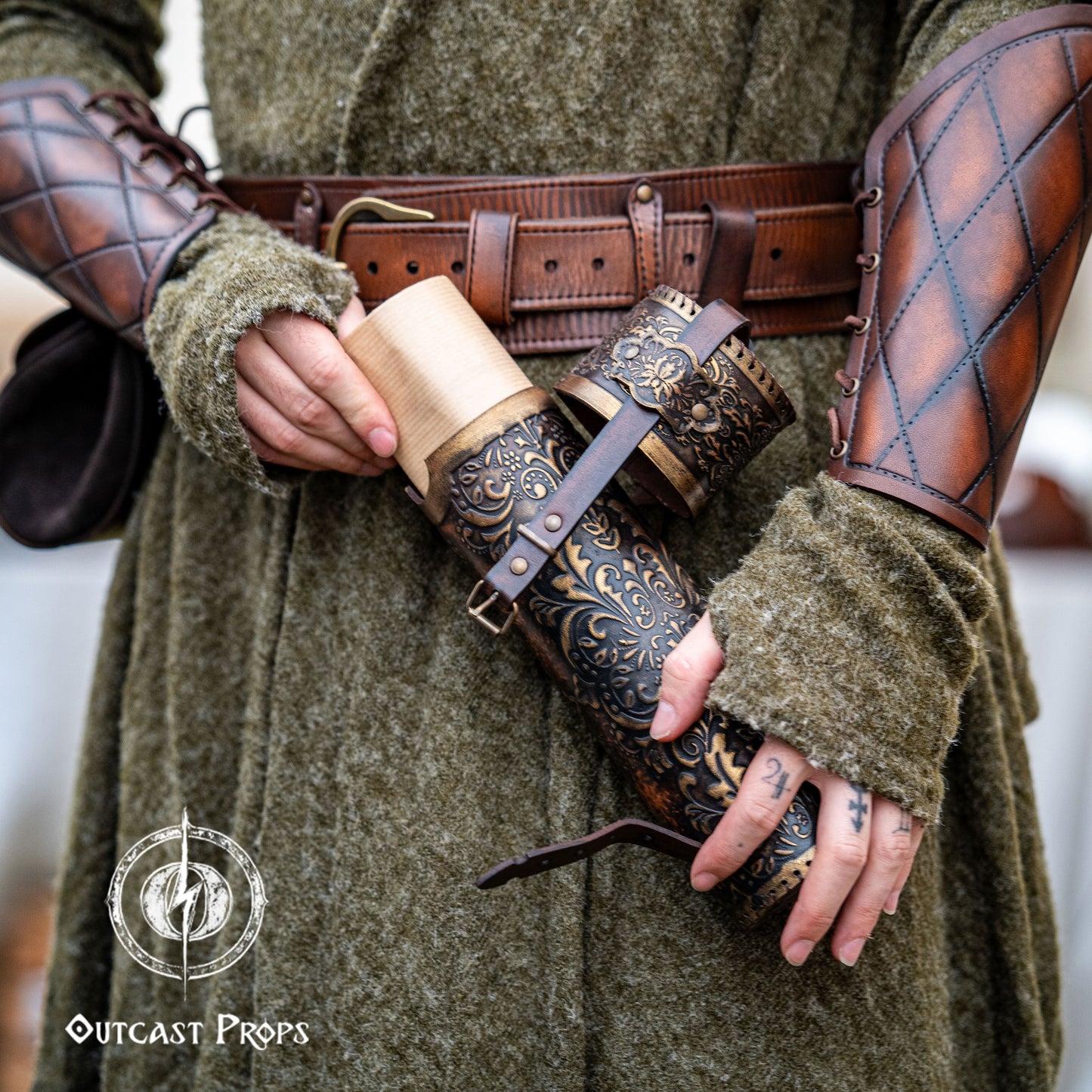Detailed view of a fantasy scroll case being opened, revealing rolled parchment inside. The leather case is brown with golden embossed decorations, worn on the hip of a medieval-style outfit with matching bracers. Perfect LARP and Renaissance fair accessory for mages, scholars, or witches. Handcrafted with vegetable-tanned leather, perfect for storing maps, secret documents or magical scrolls.
