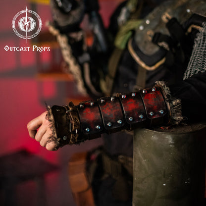Close-up of red and black leather bracer with aged steel plates and rivets. Perfect for post-apocalyptic LARP, medieval cosplay, or wasteland costumes. The rugged design and frayed fabric lining add a realistic touch to any survivor or wasteland raider outfit. Ideal for players seeking immersive costume gear with a worn and battle-ready look. Dystopian Leather & Steel Bracer: Post-Apocalyptic Arm Guard for Wasteland Cosplay and LARP