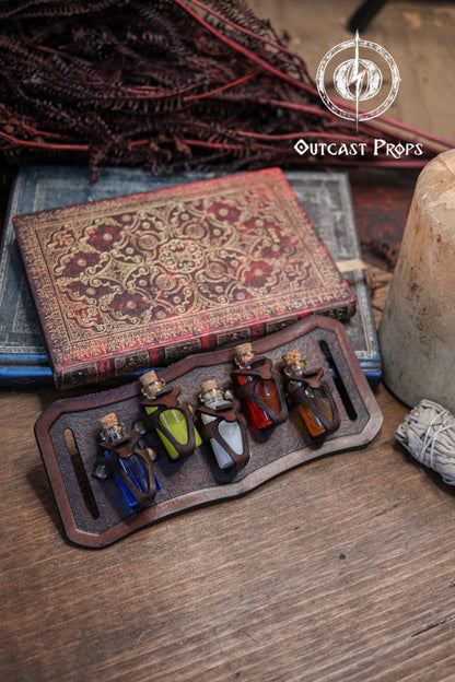 Set of small potions in a leather holder with an ornate book and decorative elements on a wooden surface. Belt Potion holder for 5 small bottles. Made of leather for adventurers, steampunk, alchemist, healers, cosplay or just to keep spices