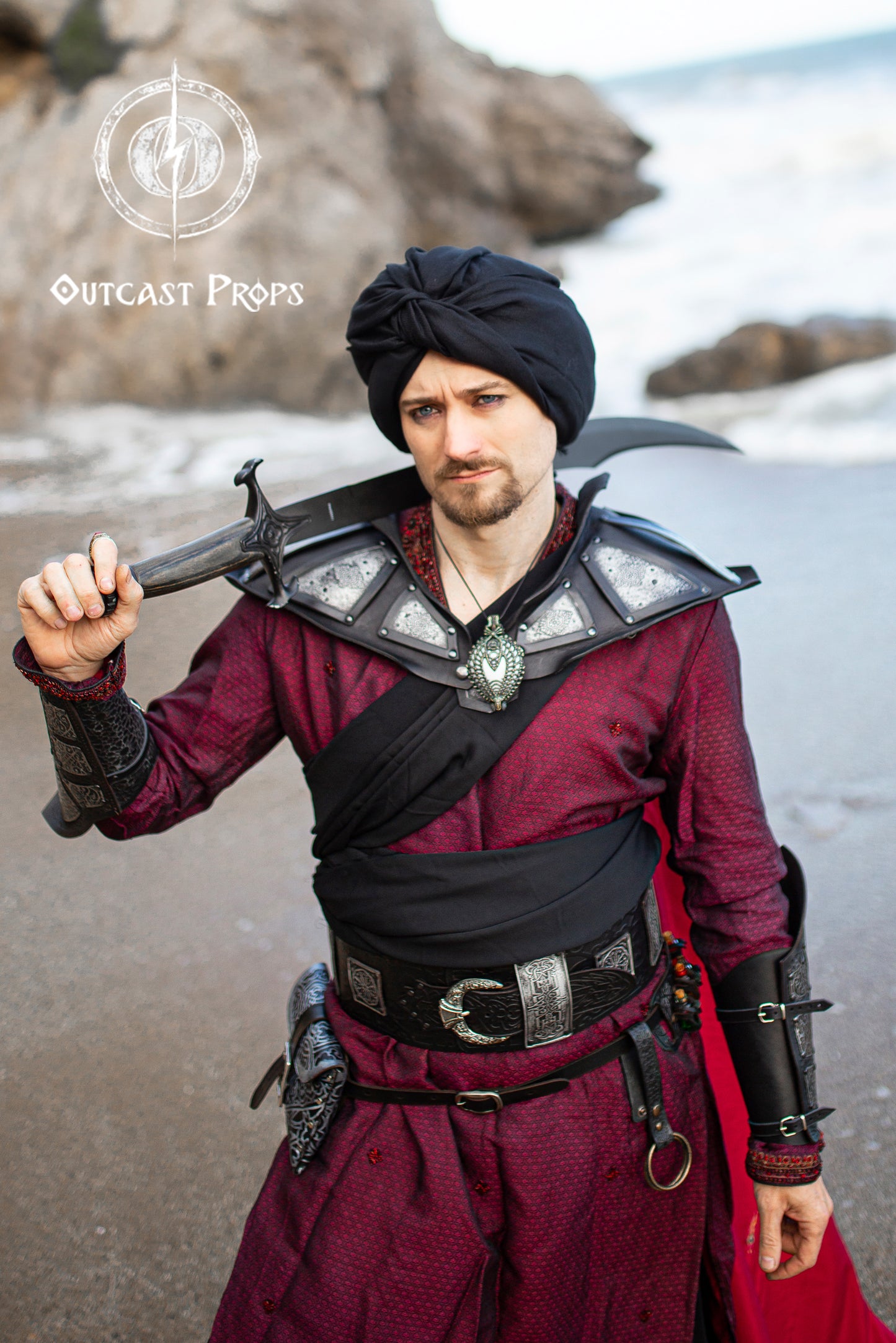 Ramattush Persian Leather Broadbelt, ornamental Arabic and Persian courts inspired, larp oriental leather belt, fantasy belt, renfaire belt. Jafar cosplay costume. Aladdin cosplay. Person in a detailed costume holding a weapon on a beach, with 'Outcast Props' branding. 