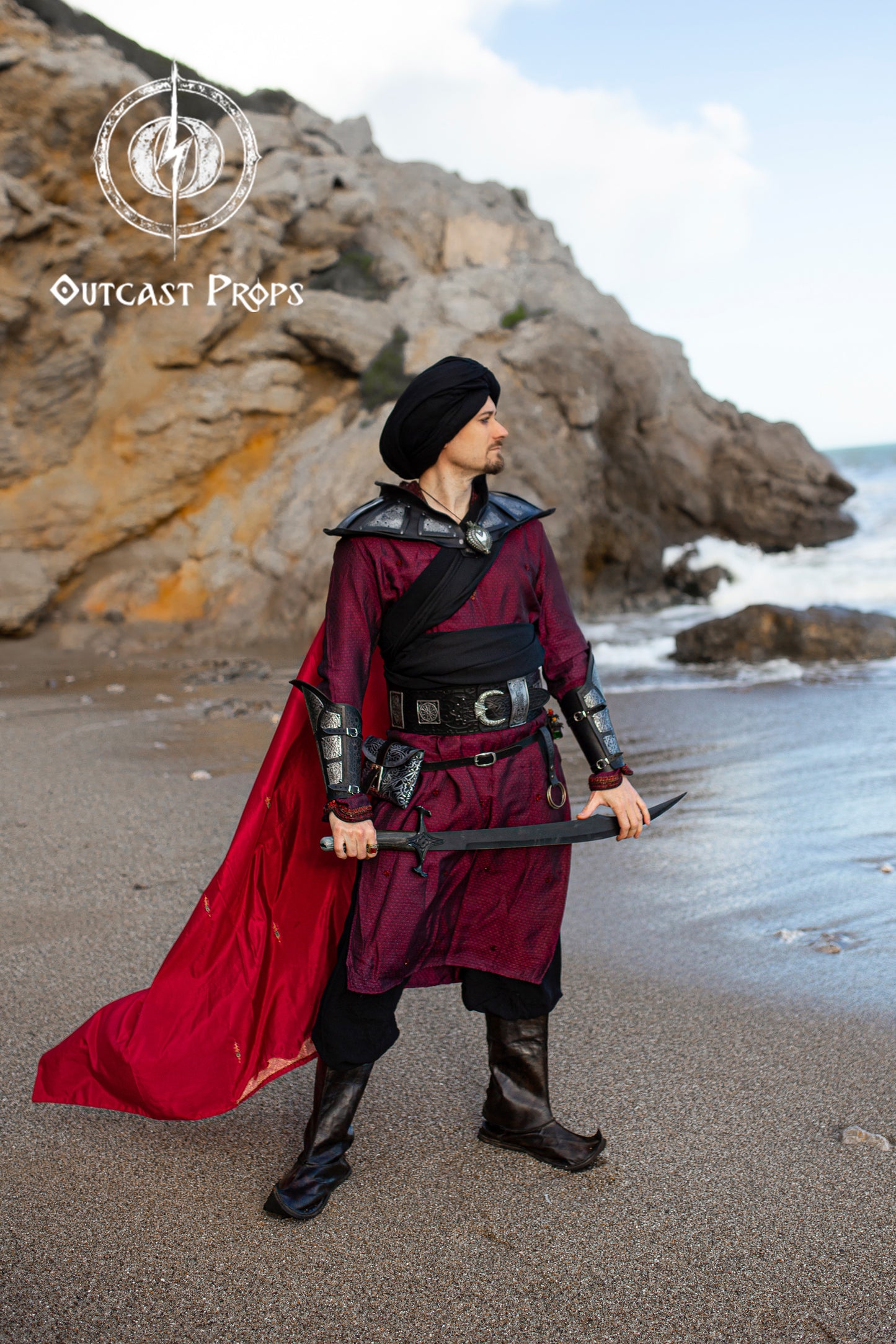 Ramattush Persian Leather Broadbelt, ornamental Arabic and Persian courts inspired, larp oriental leather belt, fantasy belt, renfaire belt. Jafar cosplay costume. Aladdin cosplay. Person in a fantasy costume with a red cape and sword on a rocky beach, featuring Outcast Props logo. 