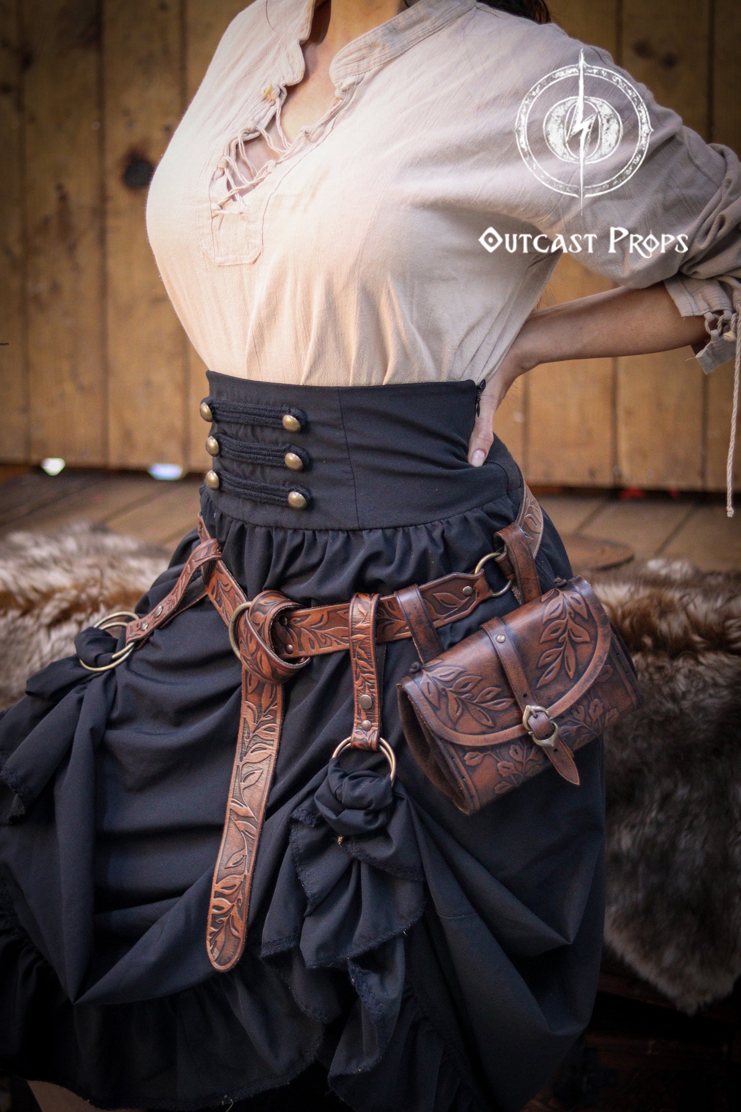 Handmade Renaissance Fair leather set featuring a floral tooled belt with O-rings, matching hip bag, and skirt hikes. Perfect for LARP, cosplay, Ren Faire, or fantasy events. Crafted from full-grain Spanish vegetable-tanned leather, dyed with natural pigments and aged by hand. Shown worn over a black skirt and medieval blouse, combining elegance and practicality for dancing, working booths, or roaming through festivals.