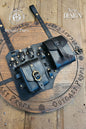 Close view of the new double pouch leather leg holster by Outcast Props, shown on a workbench circle board. Includes potion vials, embossed details, reinforced straps, and aged brass buckles. Made from full grain vegetable tanned leather with unique aging and painting. Ideal for LARP, cosplay, and renaissance fairs, this fantasy accessory combines durability, adjustability, and authentic medieval design. Wear on belt or thigh. Smooth edges add comfort. Suits rogues, alchemists, and adventurers..