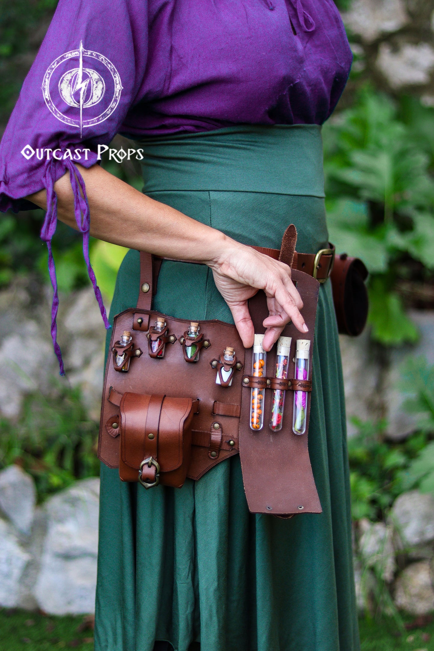 Person wearing a purple top and green skirt with a brown leather belt holding bottles. Leather Leg Harness Potion Holster: Alchemist LARP Steampunk Costume Accessory for Witch Herbologist
