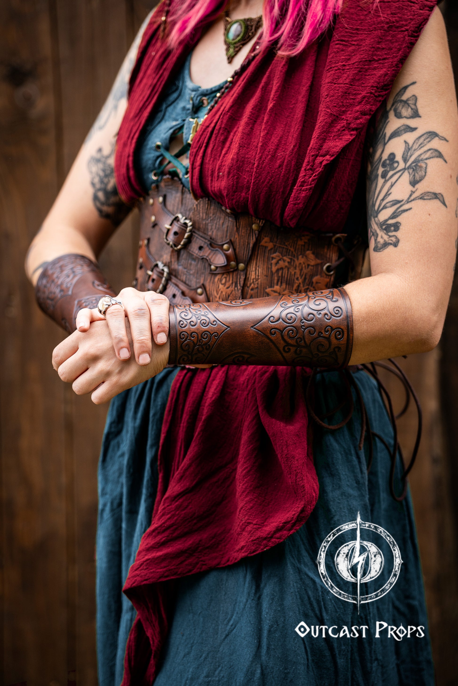 Person wearing a red scarf, leather arm guard, and blue top with a wooden background. Shadowbinder bracer for mages & wizards, sorcerer vambarce for larp costume and wizardry cosplay leather witchcraft handmade