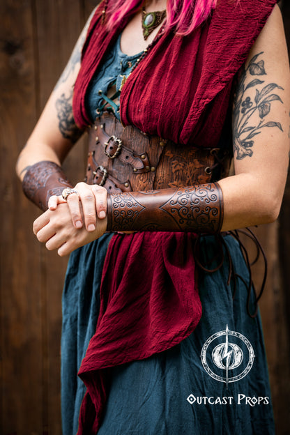 Person wearing a red scarf, leather arm guard, and blue top with a wooden background. Shadowbinder bracer for mages & wizards, sorcerer vambarce for larp costume and wizardry cosplay leather witchcraft handmade