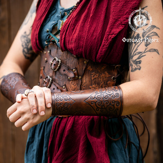 Person wearing a detailed leather bracer with tattoos and a red cloth, branded 'Outcast Props'. Shadowbinder bracer for mages & wizards, sorcerer vambarce for larp costume and wizardry cosplay leather witchcraft handmade