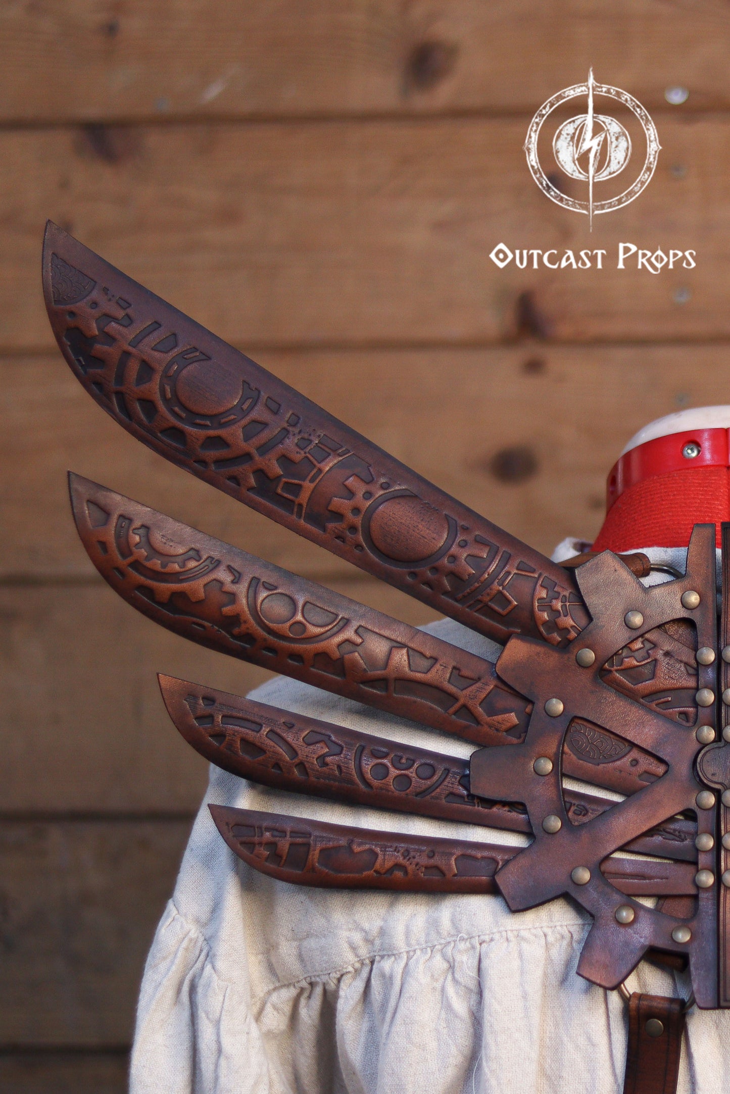 Decorative leather gauntlets with intricate patterns on a wooden background, featuring the Outcast Props logo. Steampunk Wings leather gears fairy victorian outfit burning man aviator pin up costume clock