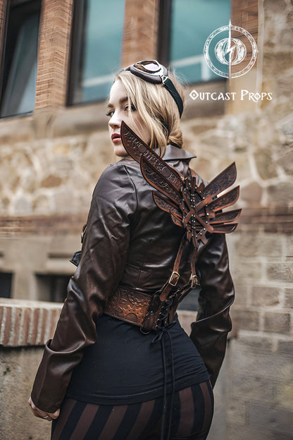 Person wearing a steampunk-style leather jacket with decorative elements, standing against a stone building. Steampunk Wings leather gears fairy victorian outfit burning man aviator pin up costume clock