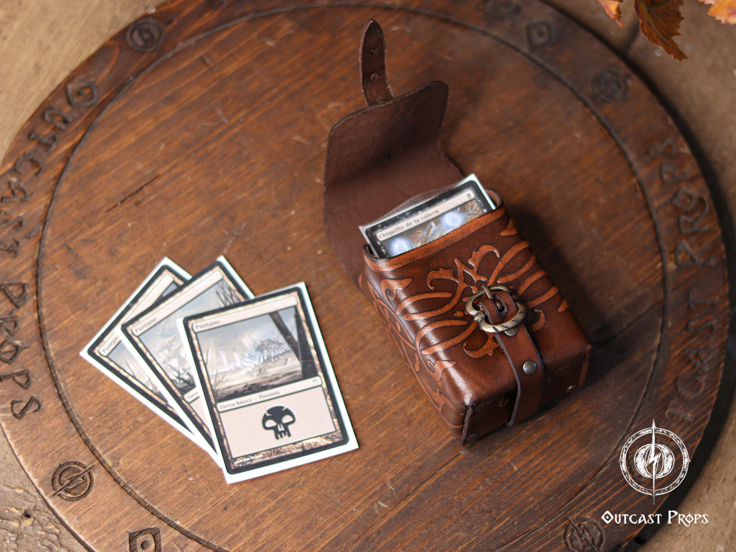 Top view of an ornated medieval leather belt pouch next to trading cards, highlighting its compact size and capacity. Handmade from vegetable-tanned leather with decorative embossing and aged finish, this leather tobacco bag works as a card deck pouch, fantasy accessory, or small everyday belt bag. A perfect gift for tabletop gamers, LARP players, and Renaissance fair lovers.