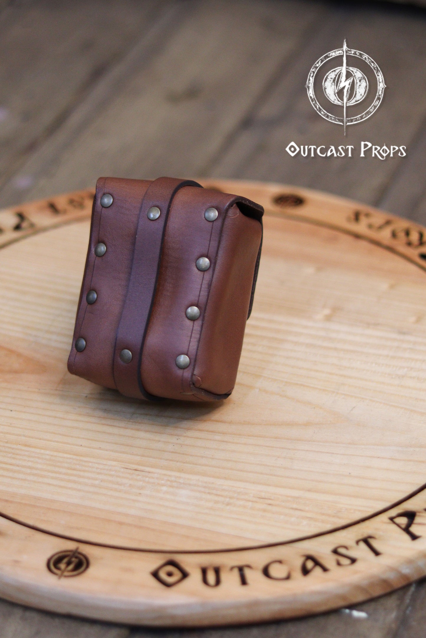 Tavern Small Leather Belt Pouch for Daily Wear LARP Renaissance Fair Viking Cosplay Medieval Accessory Steampunk Coin or Tobacco Pouch. Brown leather belt with studs on a wooden surface, featuring 'Outcast Props' branding.