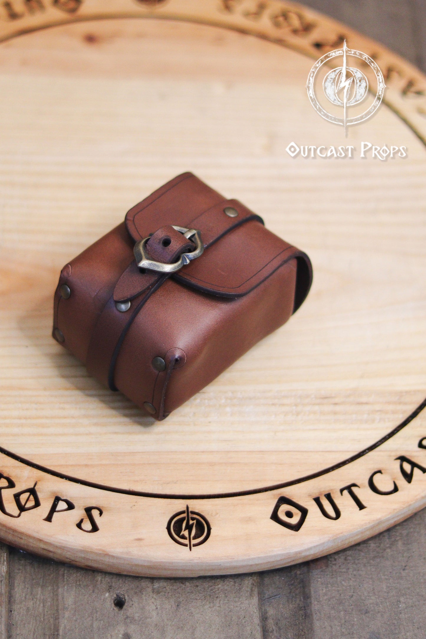 Tavern Small Leather Belt Pouch for Daily Wear LARP Renaissance Fair Viking Cosplay Medieval Accessory Steampunk Coin or Tobacco Pouch. Brown leather pouch with decorative buckle on a wooden surface with 'Outcast Props' branding.