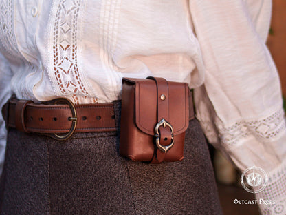 Close up of a leather belt pouch worn on the waist, highlighting the vegetable tanned leather texture, stitching, and buckle detail. This small medieval pouch works as a secure deck holder for Magic The Gathering, Pokémon, and Arkham Horror cards while keeping a historical aesthetic. Suitable for wearing multiple pouches together on the same belt, allowing modular setups. Also ideal for coins, dice, earbuds, tobacco, or keys. Perfect accessory for LARP, cosplay, Renaissance fairs, and everyday use.