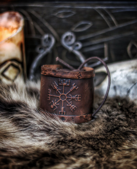 A brown leather wristband with a Viking compass design, displayed on a furry surface, featuring intricate handcrafted details. Vegvisir Leather Wristband, Galdrastafir Viking Bracelet,  Icelandic way finder rune leather embossed cuff, LARP, cosplay