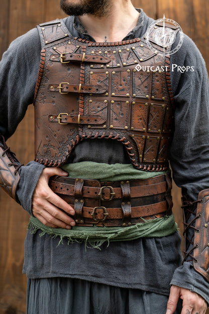 Person wearing a detailed leather armor vest with 'Outcast Props' branding. Close-up of a detailed costume with leather straps and a green cloth, branded 'Outcast Props'.  Veteran Leather Belt premium vegetable-tanned, worn by raiders and mercenaries.
