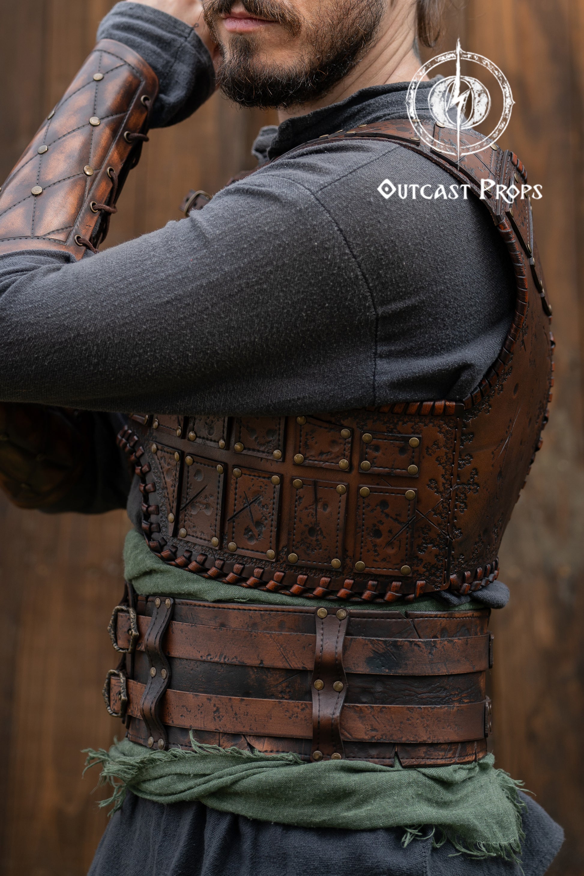 Person wearing a detailed leather armor vest with 'Outcast Props' branding. Close-up of a detailed costume with leather straps and a green cloth, branded 'Outcast Props'.  Veteran Leather Belt premium vegetable-tanned, worn by raiders and mercenaries.