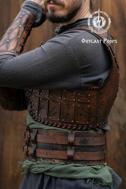 Person wearing a detailed leather armor vest with 'Outcast Props' branding. Close-up of a detailed costume with leather straps and a green cloth, branded 'Outcast Props'.  Veteran Leather Belt premium vegetable-tanned, worn by raiders and mercenaries.