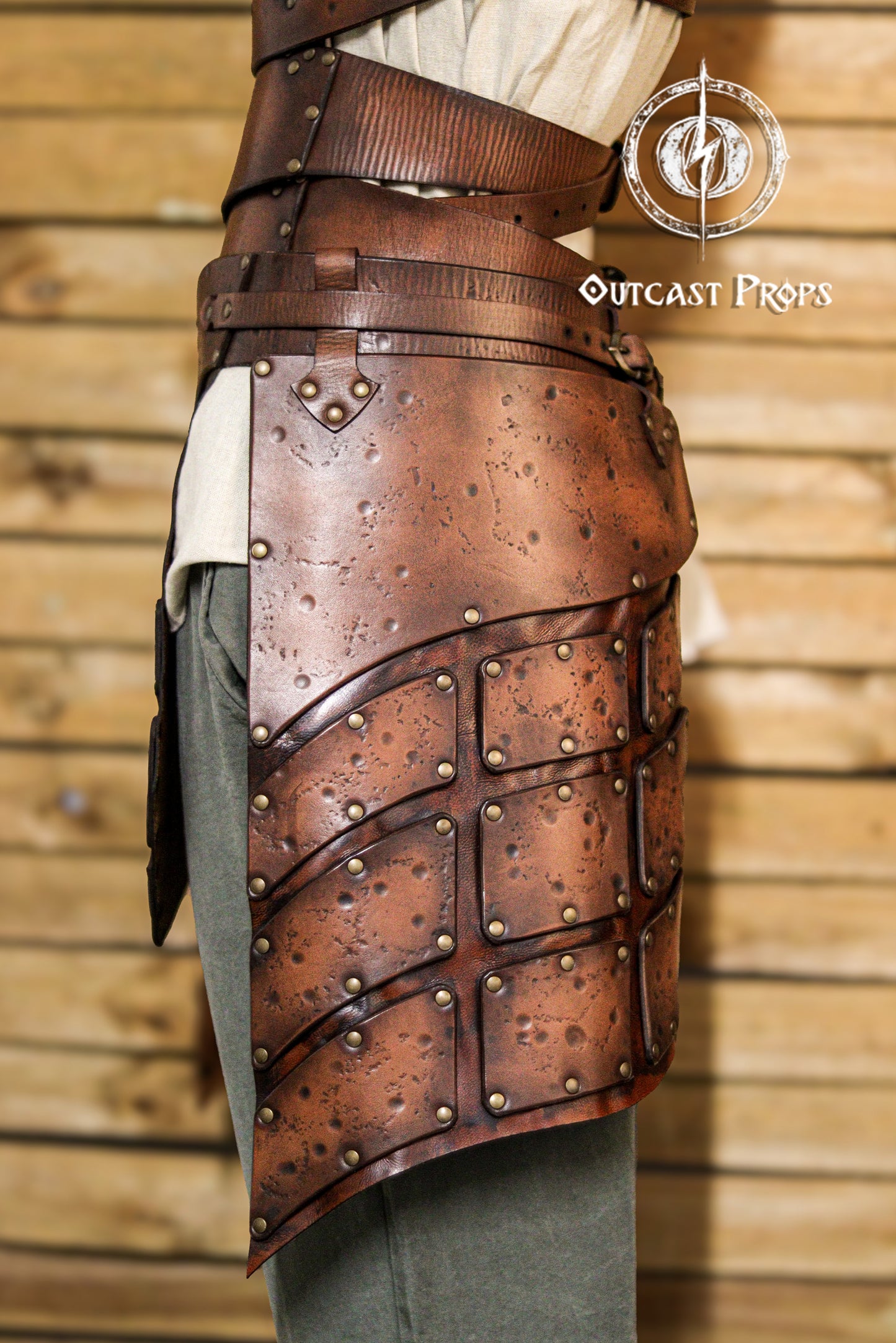 Close-up side view of brown leather tassets with brass rivets and distressed finish. Perfect for female warrior costumes, this handcrafted element of a LARP armor set provides protection and mobility for fantasy, viking or ranger characters.