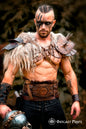 Viking leather armor belt with Valknut engraving worn by a male model in fur shoulder armor. Perfect for barbarian cosplay outfit, celtic fantasy belt, or medieval warrior armor. The embossed wide belt features decorative rivets and a central symbol, set in a rustic Viking hut. Ideal for LARP, renfaire costume wide, or fantasy events.