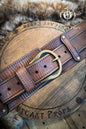 Brown leather belt with brass buckle on a wooden surface, featuring 'Outcast Props' branding. Brown leather belt with brass buckle on a wooden surface, branded 'Outcast Props'. Medieval broadbelt for larp or cosplay. Elegant leather belt. 