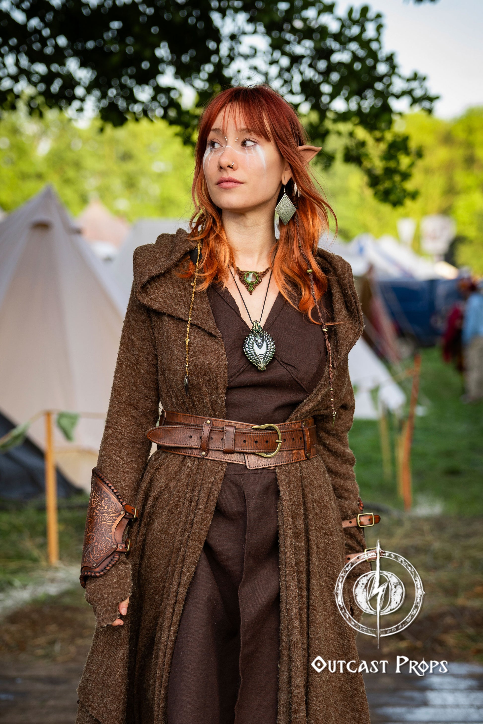 Person in a brown coat with a belt and leather pouches standing outdoors with tents in the background. Celtic knot leather belt silver buckle larp belt for ren fair fantasy costume celtic belt unisex leather belt for renaissance outfit